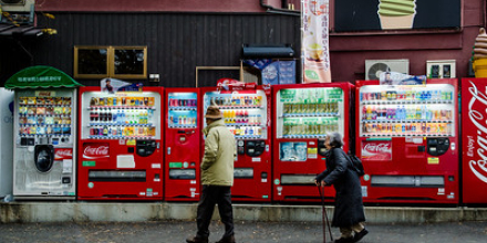 An elderly couple walk in front of a row of vending machines in Miyajima, Japan on 4 January 2014.