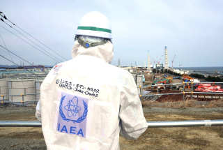 An IAEA team leader looks at contaminated water tanks and the Unit 4 and Unit 3 reactor buildings during a tour of the tsunami-stricken Fukushima Daiichi Nuclear Power Station on 11 February 2015.