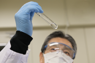A Japanese scientist holding up test vial confirming the result of a test.
