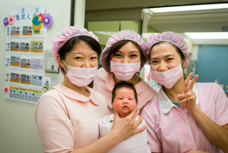 Three Japanese nurses and an infant pose for a photo.