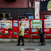 An elderly couple walk in front of a row of vending machines in Miyajima, Japan on 4 January 2014.